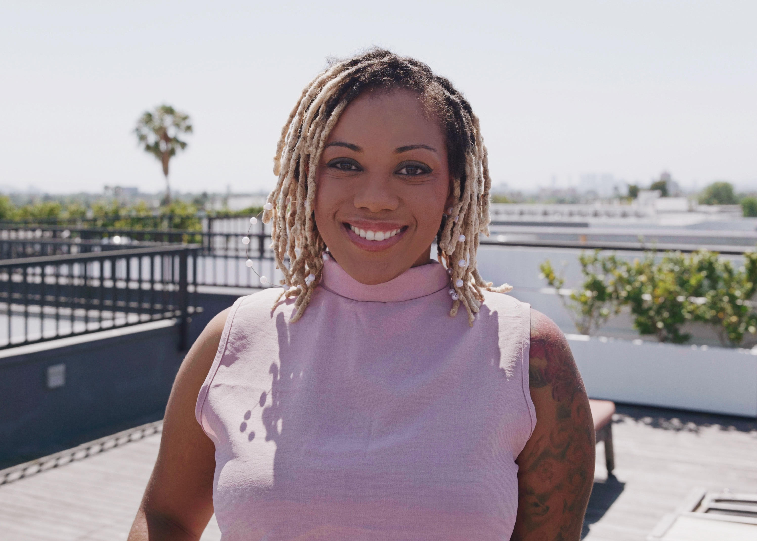 Jhaynane Bastien, founder and creative director of Lily House Studio, smiling on a Los Angeles rooftop