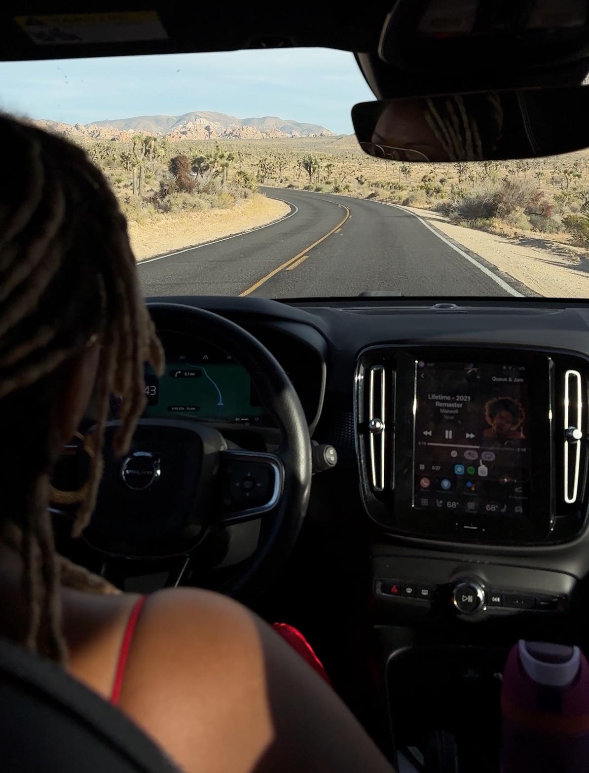 Jhaynane Bastien driving through Joshua Tree — road ahead, desert landscape, Volvo interior